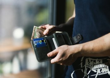 photograph of person holding black leather wallet with money